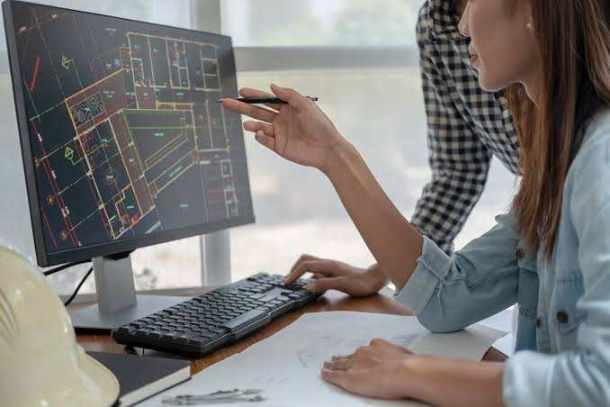 Designer reviewing a CAD floor-plan layout on a large monitor