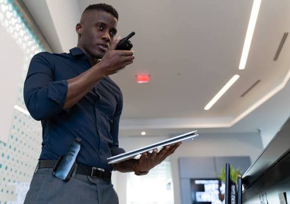 Building security officer using a two-way radio and tablet to monitor a commercial lobby