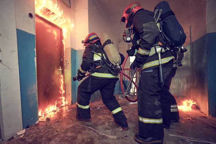 Firefighters entering a burning building interior with breathing apparatus