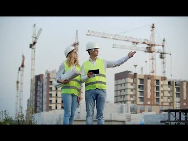 Construction project team reviewing a new high-rise development under a row of tower cranes