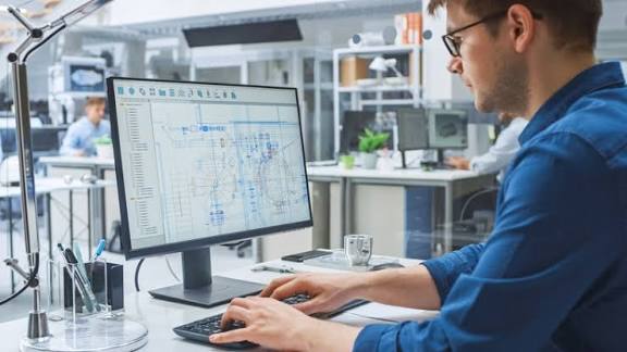 Design engineer working on AutoCAD plan set at a dual-monitor workstation