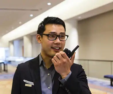 Hotel staff member using a two-way radio in a conference center lobby