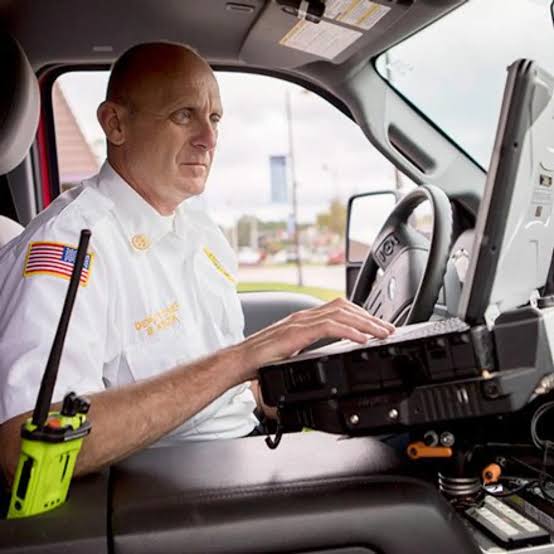 Fire chief working from a command vehicle laptop with portable radio at his side